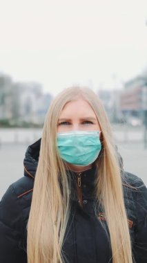 Coronavirus salgını: Sokakta yürüyen maskeli sarışın kadın