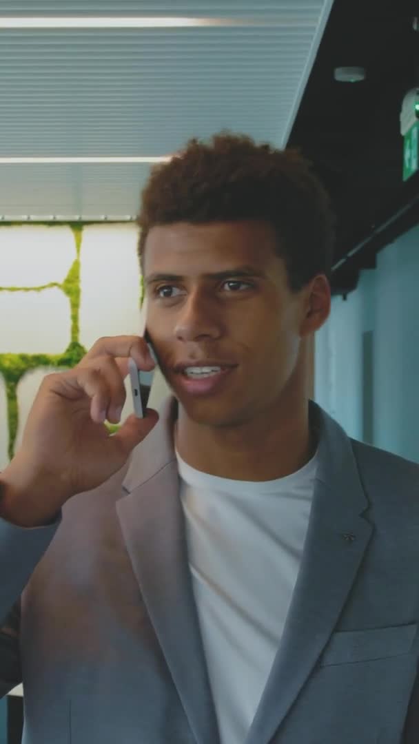 Черный бизнесмен говорит по телефону. Красивый афроамериканец в костюме, которому звонят в офис и уверенно смотрят в сторону. . — стоковое видео