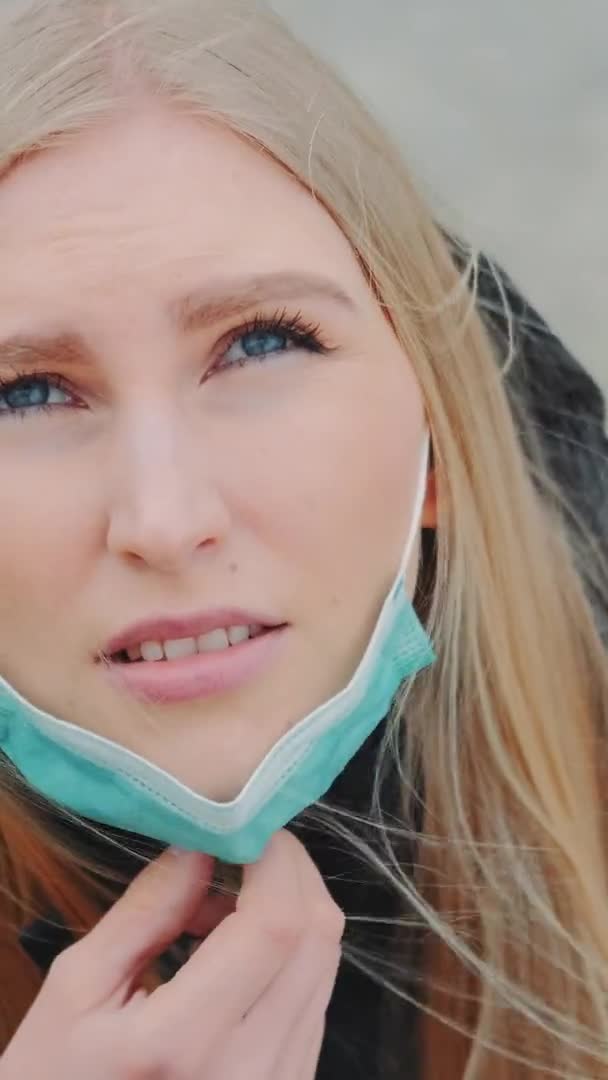 Crane shot of blonde woman looking into the sky and putting on medical mask — Stock Video