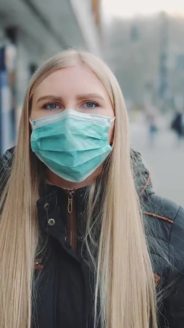 Fiatal szőke nő, védőorvosi maszkot visel az utcán. — Stock videók