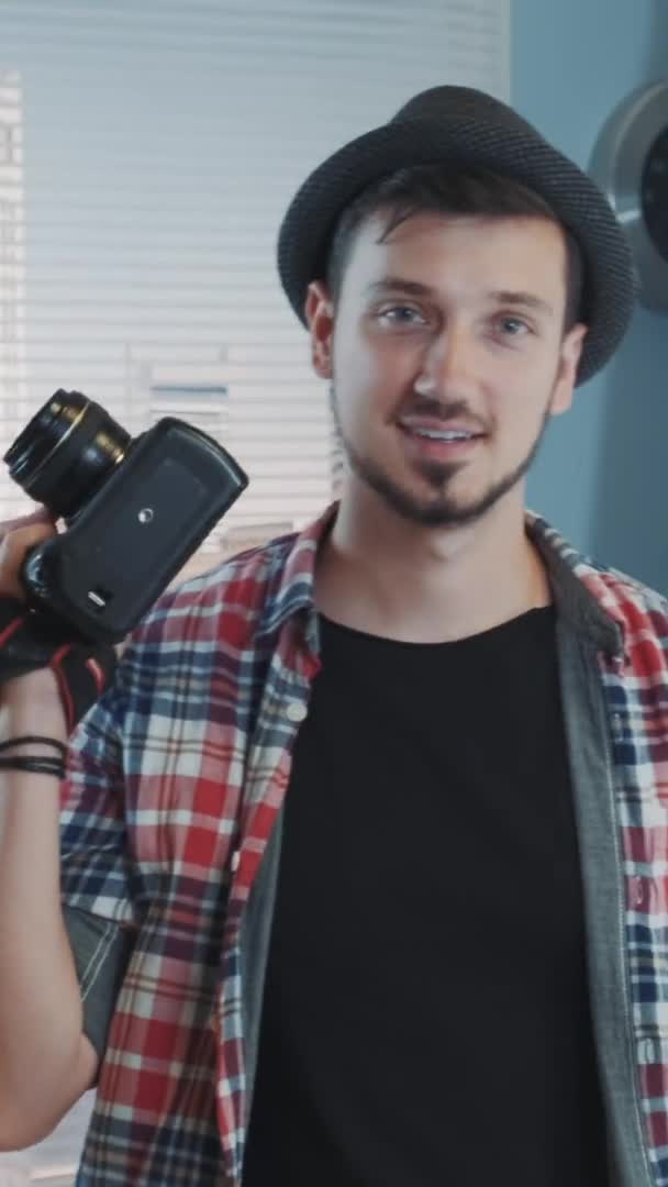 Retrato de joven fotógrafo en ropa casual con cámara profesional sonriendo y posando — Vídeo de stock