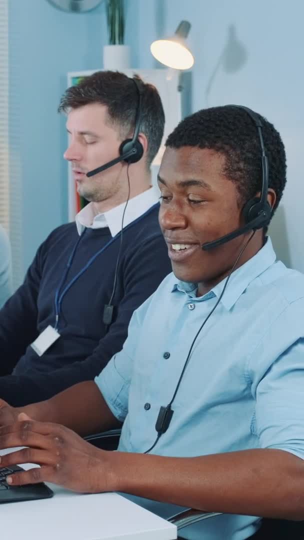 अंतर्राष्ट्रीय ग्राहक से बात करके व्यस्त कॉल सेंटर में काम करने वाले काले ग्राहक सहायता एजेंट — स्टॉक वीडियो