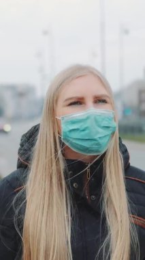 Tıbbi koronavirüs maskeli endişeli bir kadın sokakta yürüyor.