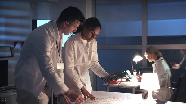 기술 연구소: 실험실에서 전자 칠판으로 일하고 전자 제어 전자 장치를 조작하는 흰색 코트에 인종 전자 기술자를 혼합 한 모습 — 스톡 사진