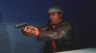 Siyah suçlunun silahı kapıp polislere zarar vermekle tehdit ettiği yakın plan.