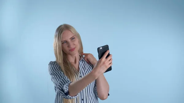 Houkutteleva blondi nainen tekee selfie älypuhelimella sinisellä taustalla — kuvapankkivalokuva