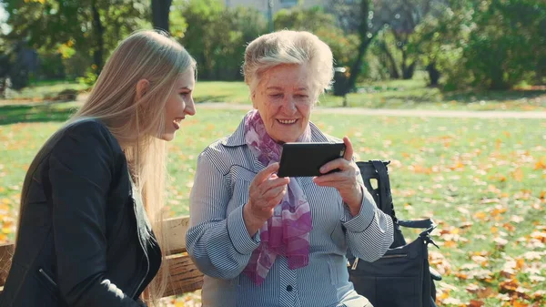 Yaşlı büyükanne akıllı telefondan torununa fotoğraflarını gösteriyor.