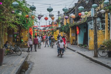 Renkli ipek fenerlerle süslenmiş eski caddenin harika manzarası. Geleneksel Vietnamlılar Hoi Antik Kasabası boyunca yürürken kapanır..