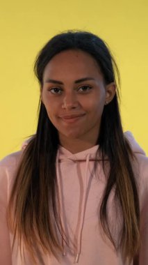 Güzel melez kadın sarı arka planda sessiz bir jest yapıyor..