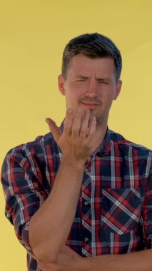 Huzursuz genç adam olumsuz duygular gösteriyor ve baş parmağını kaldırıyor..