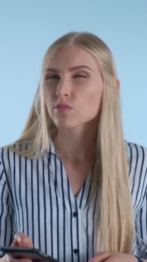 Sarışın genç bir kadın mavi arka planda bir şey düşünürken çenesini eliyle tutuyor..