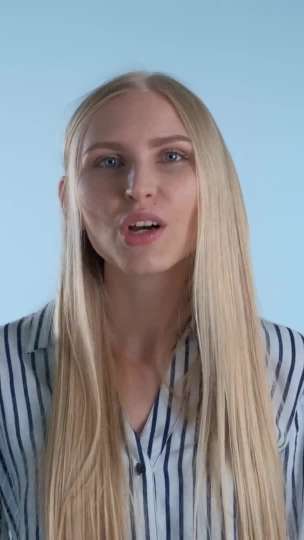 Удивительная блондинка делает жест молчания на синем фоне — стоковое видео