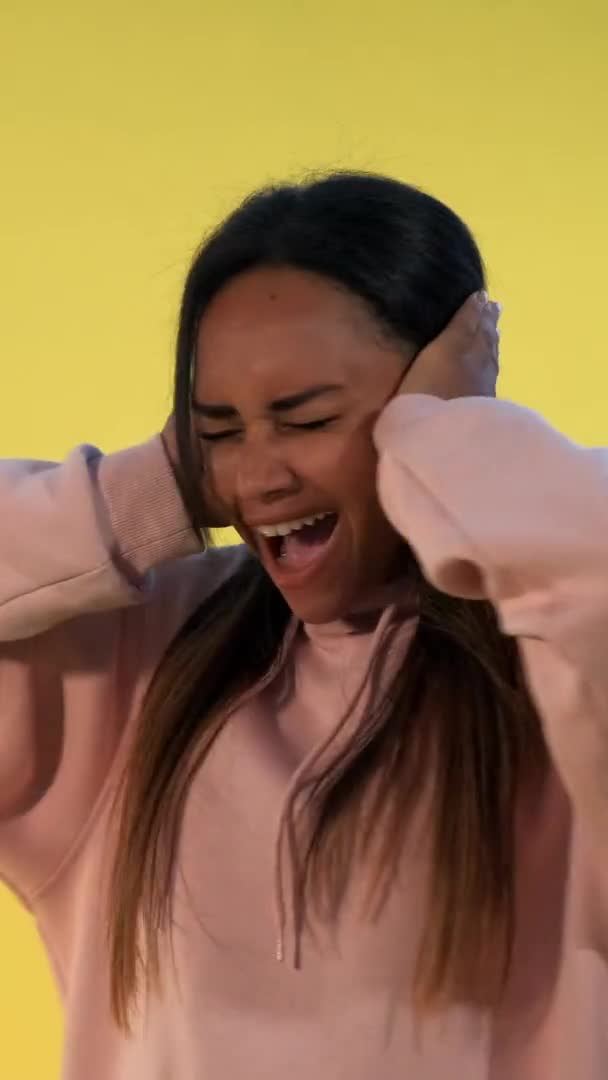 Desperate african woman screaming and covering ears on yellow background — Stock Video