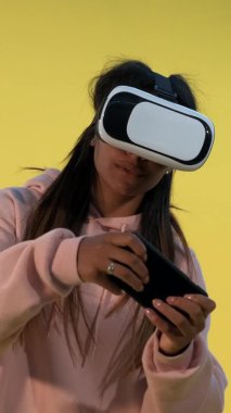 Sanal gerçeklik gözlüklü çok ırklı kız akıllı telefondan online oyunlar oynuyor.