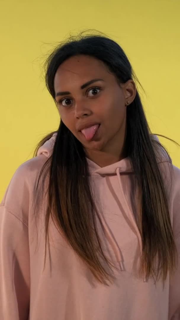 Багатоетнічна дівчина робить смішні обличчя на жовтому тлі . — стокове відео