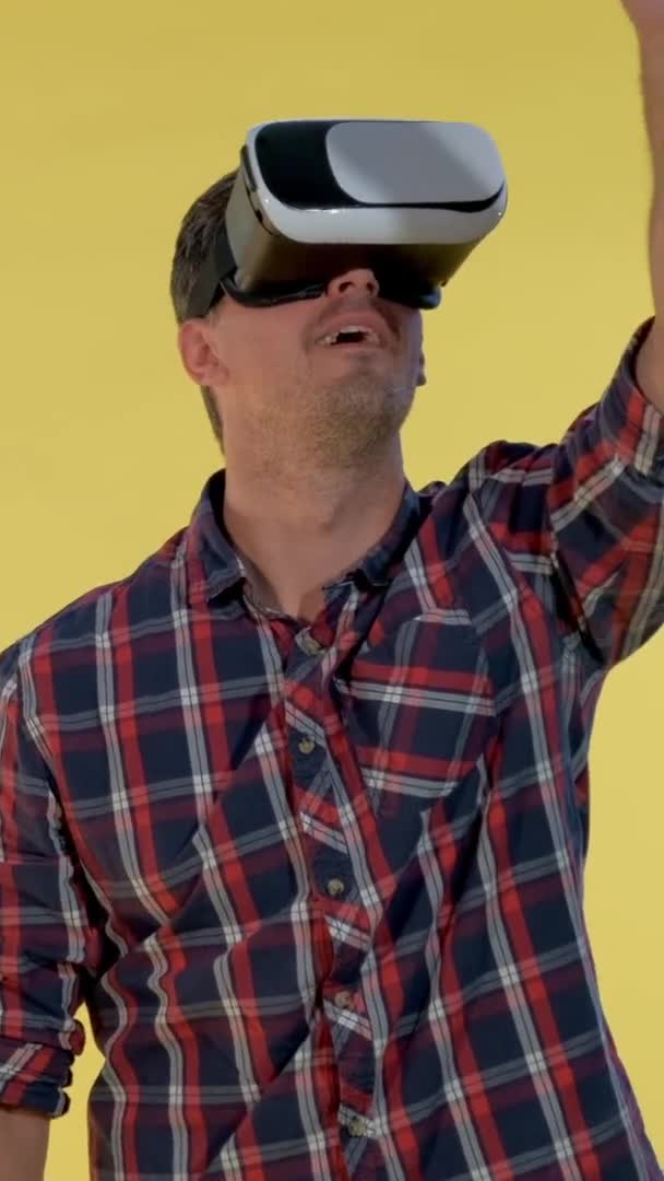 Uomo dai capelli scuri che utilizza occhiali di realtà virtuale mentre in piedi sullo sfondo giallo . — Video Stock