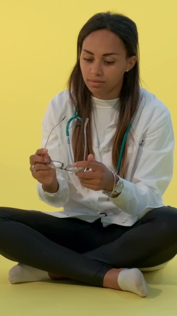 Doctora negra cansada quitándose los anteojos y el estetoscopio — Vídeos de Stock
