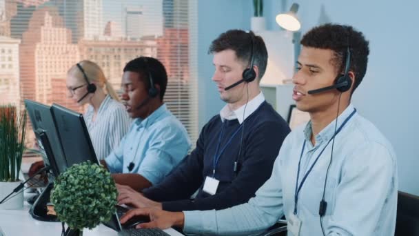 Medium shot van Multiraciale call center agenten praten met de klanten in headset — Stockvideo