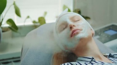 Güzellik salonundaki kozmetik buharlı profesyonel yüz bakımı ile orta boy yakın çekim.
