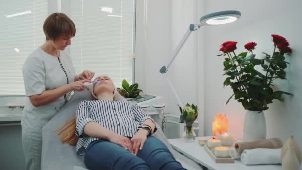 Профессиональный косметолог делает кавитационный пилинг на лице молодой женщины — стоковое видео