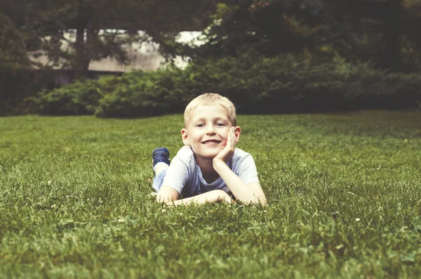 Ragazzo sorridente su un'erba verde — Foto Stock