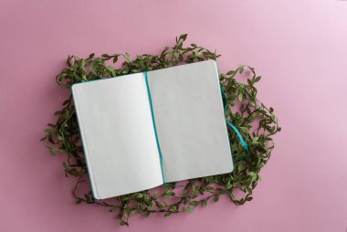 Minimalist düz, yeşil bitkinin üzerinde boş bir defter vardı.