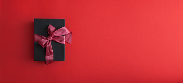 Black gift box wrapped with crimson ribbon