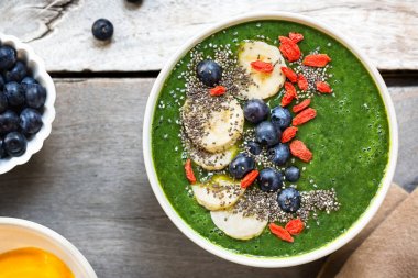 Yapılan ıspanak, muz, yaban mersini ile bir kase içinde Mango yeşil smoothie muz, Goji berry ve Chia tohum tepesi