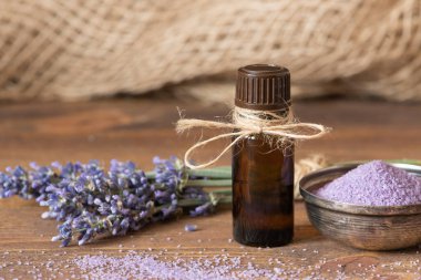 Ahşap arka planda lavanta çiçekleri, banyo tuzu ve lavanta yağı..