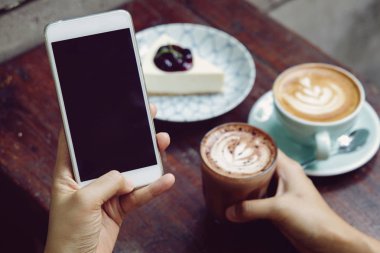 Kadın veya erkek el kahve yudumlarken Cafe'de smartphone kullanarak yakın çekim resmin. Cep telefonu, sosyal ağ kavramı üzerinden metin mesajı yazmaya. Smartphone mockup.