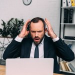 Портрет напруженого бізнесмена на робочому місці з ноутбуком в офісі