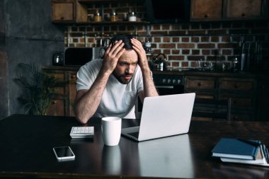 portrait of overworked freelancer remote working at table with laptop in kitchen at home clipart