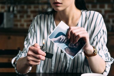 cropped shot of young woman burning photo card of ex-boyfriend clipart