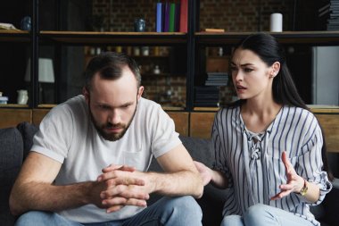 kanepede oturan ve uzakta eşi onu basarak arayan genç adam depresif