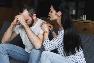 young wife asking forgiveness from husband after quarrel at home clipart