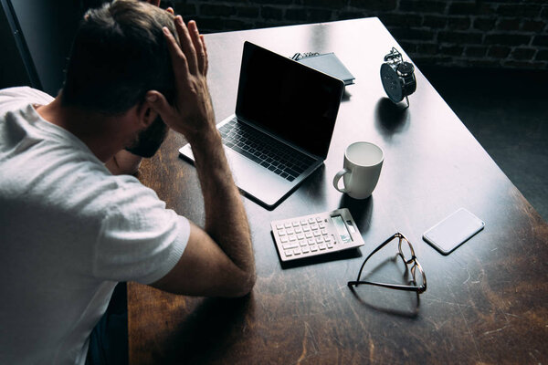 partial view of stressed and overworked freelancer remote at table with laptop and calculator in kitchen at home