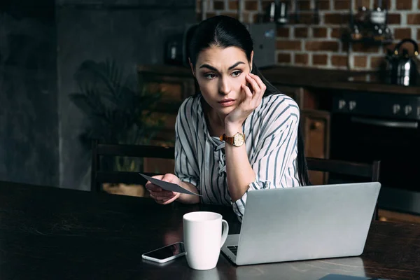 Mujer Joven Deprimida Con Teléfono Inteligente Portátil Sentado Cocina Mirando —  Fotos de Stock