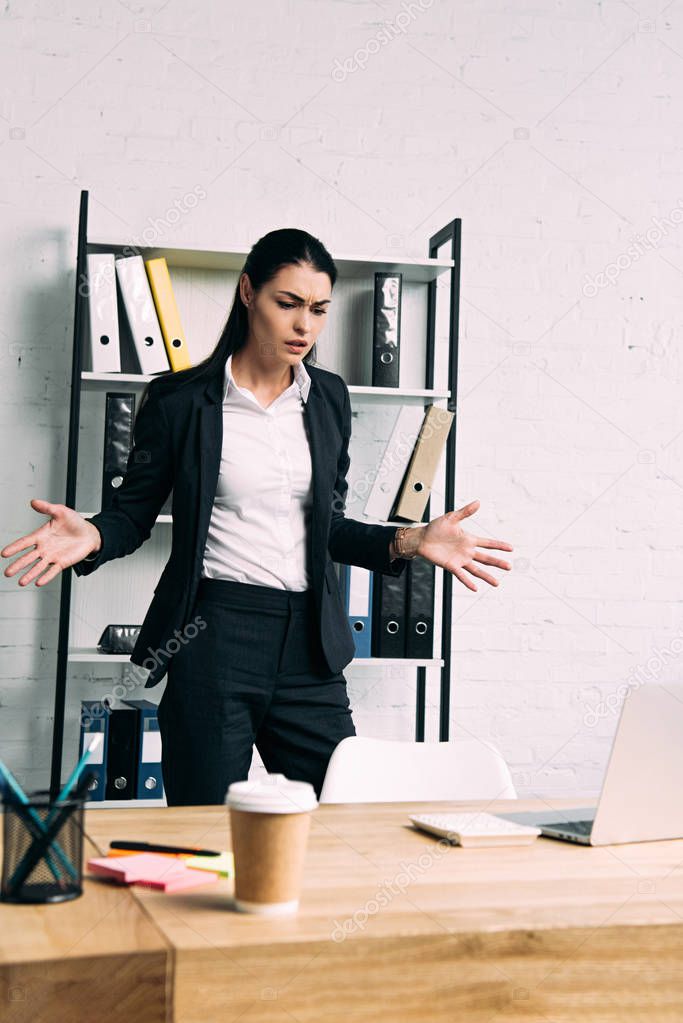 portrait of overworked businesswoman standing at workplace with laptop in office