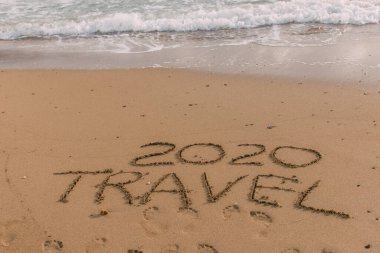 summer beach with 2020 travel lettering on sand near sea  clipart