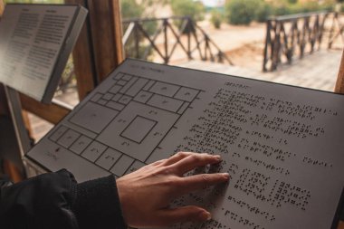 PAPHOS, CYPRUS - MARCH 31, 2020: cropped view of disabled woman reading braille text in book  clipart