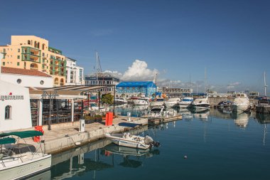 PAPHOS, CYPRUS - 31 Mart 2020: Mavi gökyüzüne karşı binaların yanındaki mavi denizde yatlar 