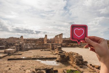 cropped view of woman holding paper heart near ancient House of Theseus  clipart
