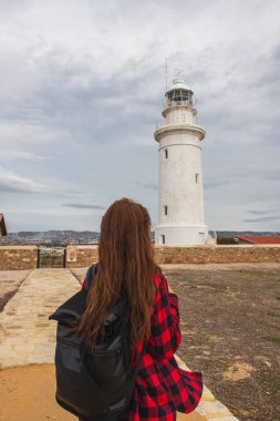 back view of woman with backpack standing near white lighthouse clipart