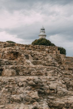 ancient archaeological park with ruins and rocks near lighthouse  clipart