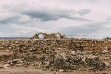 ruins of old archaeological park against sky with clouds  clipart