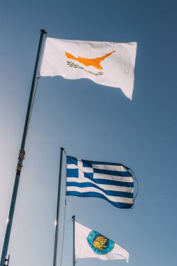 Mavi gökyüzüne karşı Yunan ve cypus ulusal bayraklarının düşük açılı görüntüsü 
