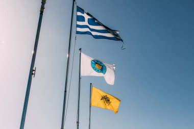 Mavi gökyüzüne karşı milli bayrak ve Yunan bayraklarının düşük açılı görüntüsü 