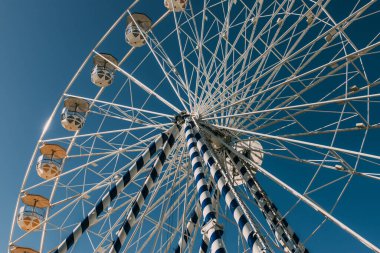 low angle view of ferris wheel against blue sky in summertime clipart