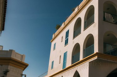 Gökyüzüne karşı mavi balkonları olan modern bina üzerine güneş ışığı