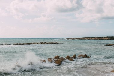 Akdeniz kıyısındaki kayalar bulutlu mavi gökyüzüne karşı 